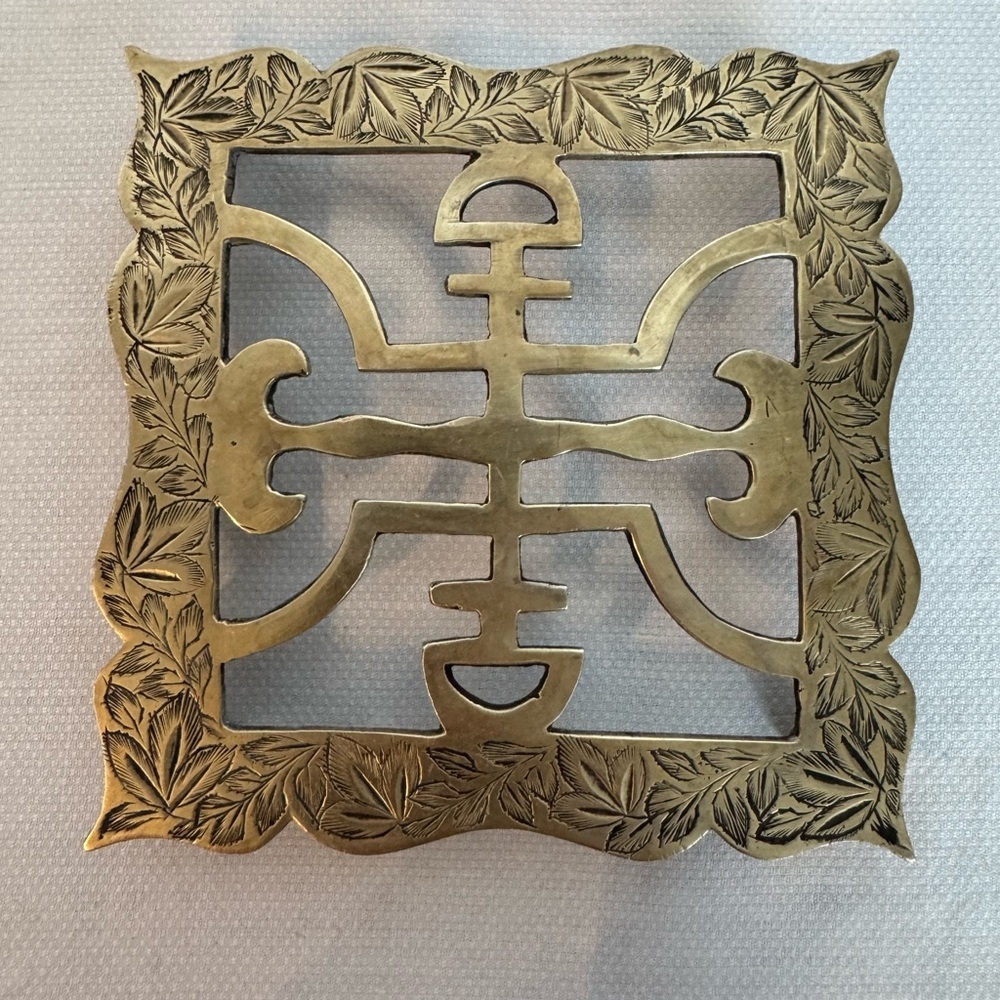 Brass trivet with etched floral border and Asian symbol design